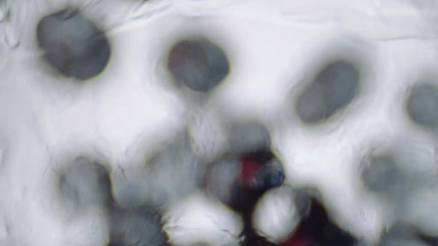 A translucent lightly textured layer ripples as it moves over gray spheres on a white surface