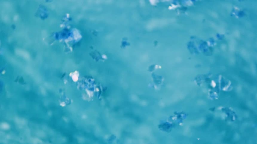 White and blue particles float on surface of blue and white fluid as it flows back and forth