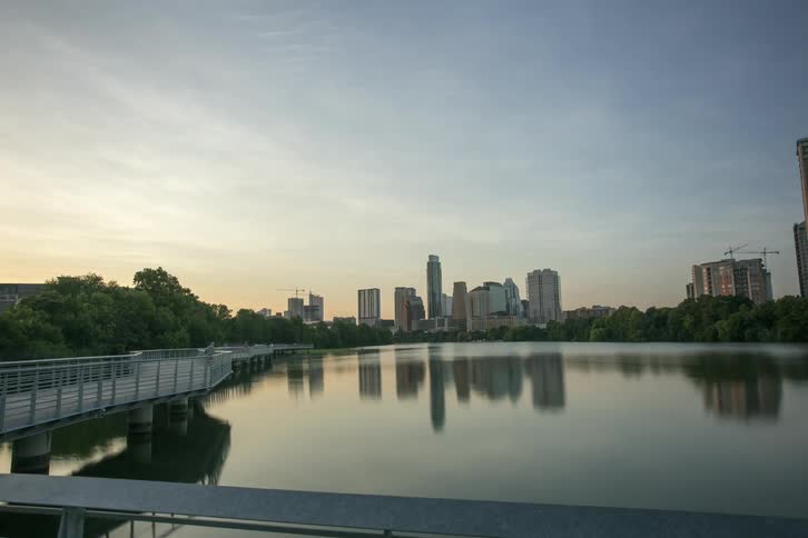 People travel across a bridge with a city in the distance