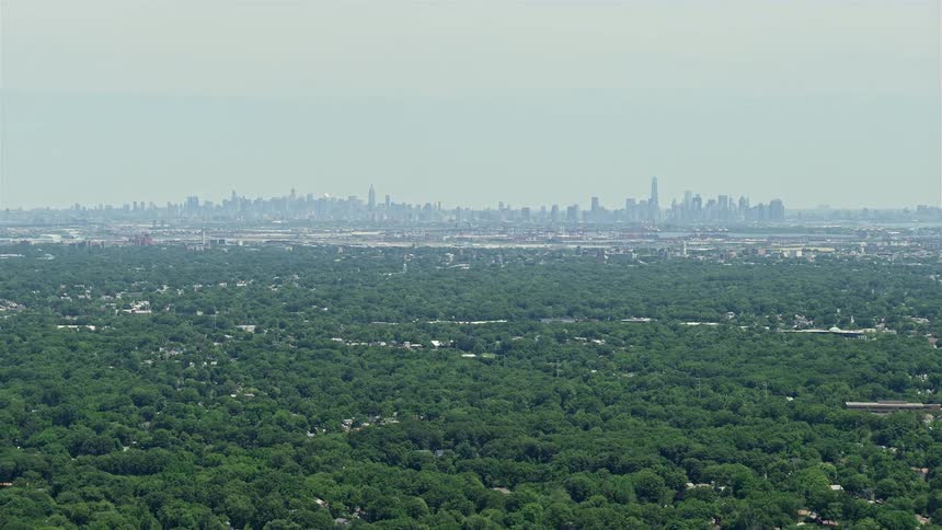 Aerial footage of Lower and Midtown Manhattans distant city skyline shot from New Jersey during the summer
