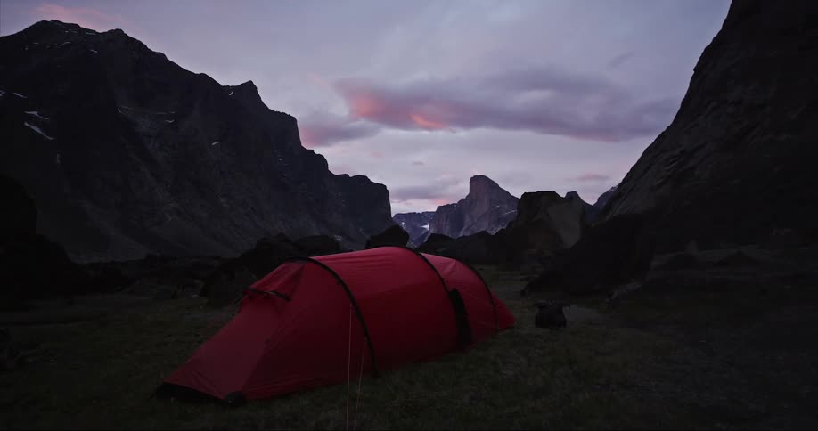 The perfect campsite - red tent in a grass meadow under the midnight sun on Baffin Island in Auyuittuq National Park