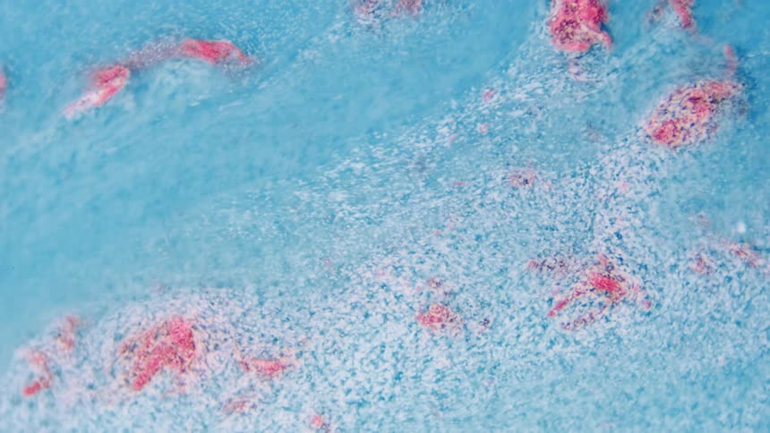 The blue liquid flows over the pink rocks