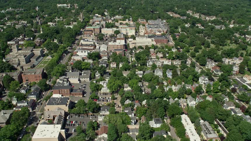 Approaching sunny shops and restaurants in Princeton New Jersey via an aerial flyover of densely populated residential areas