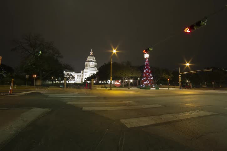 People and cars travel on a street at night