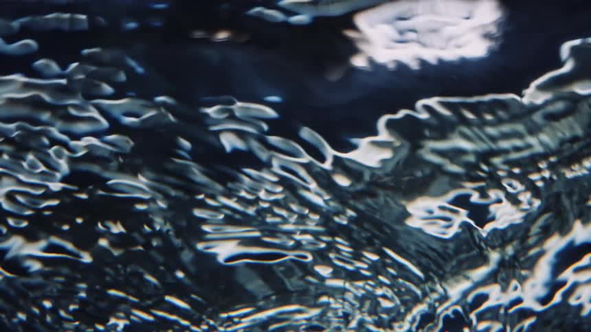 Dark liquid swirls and ripples creating light and shadows