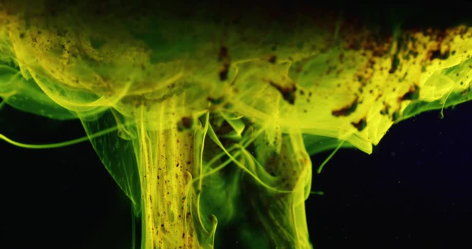 Green liquid with particles on a black background moves in slow motion