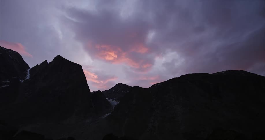 Silhouetted mountains with purple and pink clouds at sunset in the Arctic Circle polar climate
