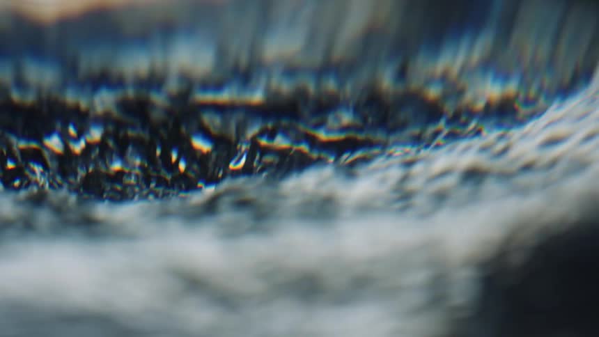 Light reflects on the ripples of a liquid substance as it swirls and moves