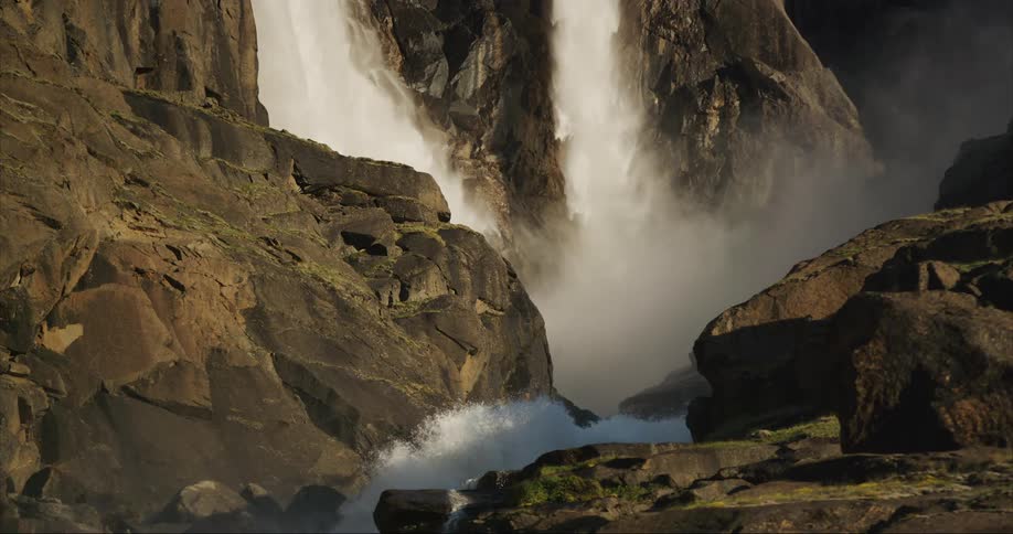 Landscape of waterfall cascading down mountainside and exploding out the bottom of the frame