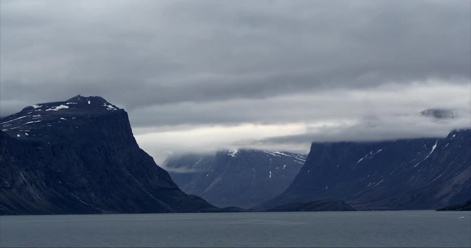 Dark clouds floating above snowy mountains on the shoreline of the Arctic Ocean