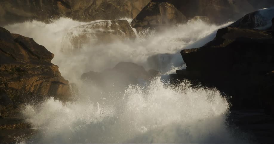 Slow tilt up showing a massive waterfall cascading down a granite cliff face