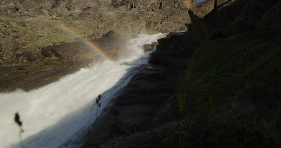 A rainbow over rushing and cascading water in a canyon