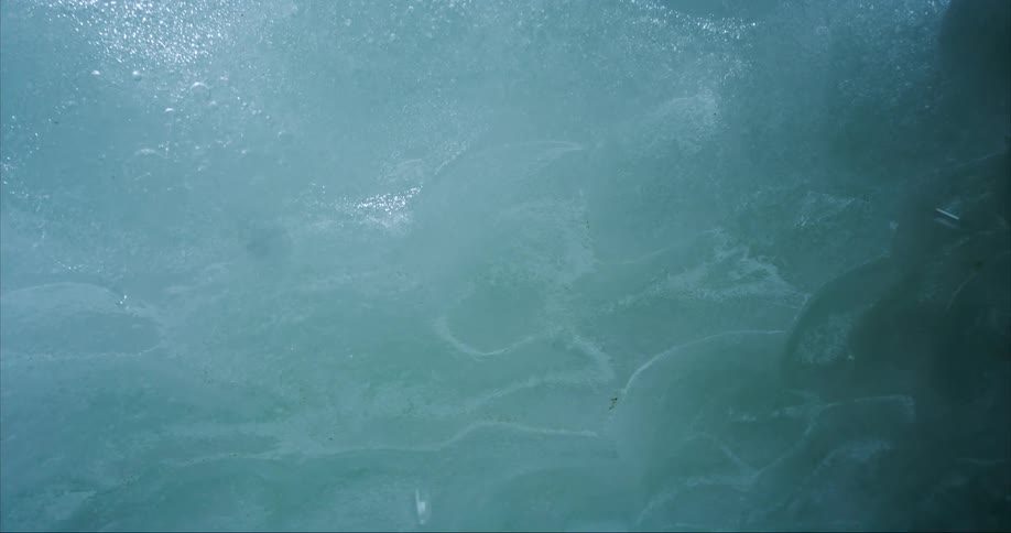 Water drips from a thick layer of glacier ice