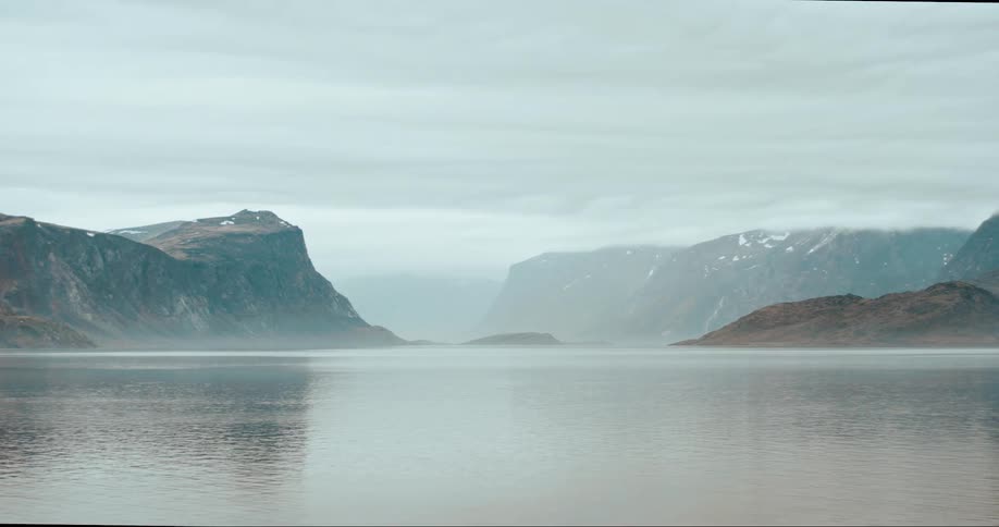 Water rippling on the arctic ocean with mountains in the distance on a cloudy stormy winter day