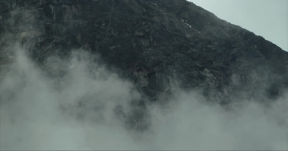 Mist moving away to reveal a cliffside on a stormy day in the Arctic tundra