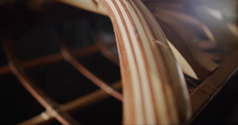 A light shines on the wooden frame of a hand built traditional sea kayak