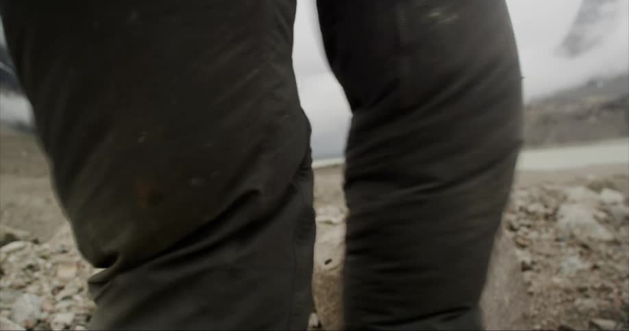 Heavy winds whip a persons pants around their legs while they stand on the arctic tundra in a severe storm