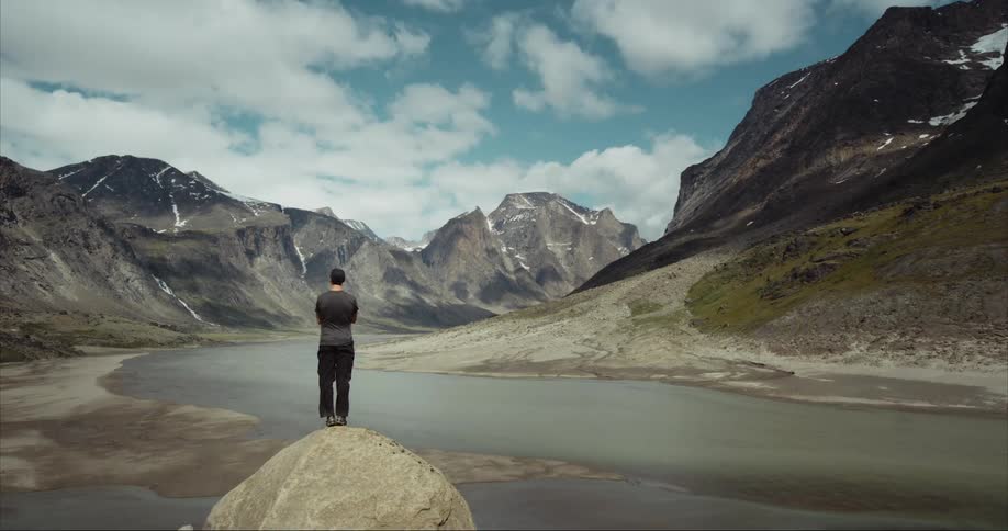 A man ponders the awesome glacial valley on Baffin Island in the arctic circle