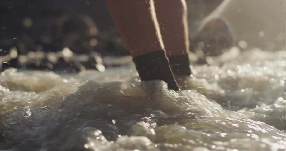 A man is walking through a flooded river on a trekking trip in the arctic circle