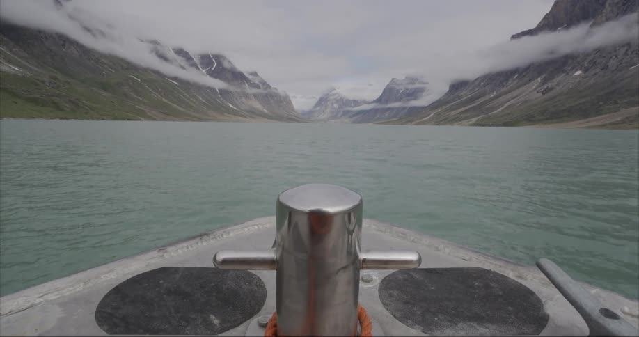 Boat speeds towards a u shaped glacier valley in the Arctic Ocean