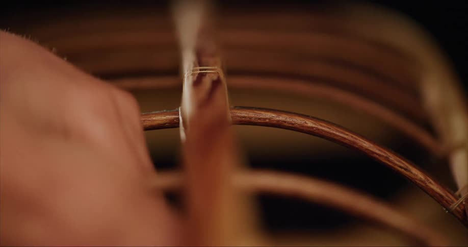 A person wrapping thread around the frame of their traditional sea kayak