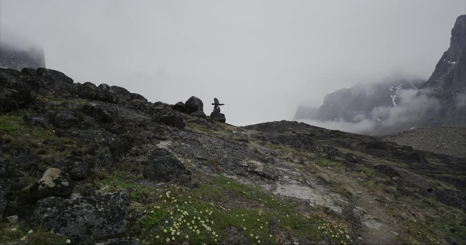 An Inukshuk marks the trail on a foggy and stormy day on Baffin Island