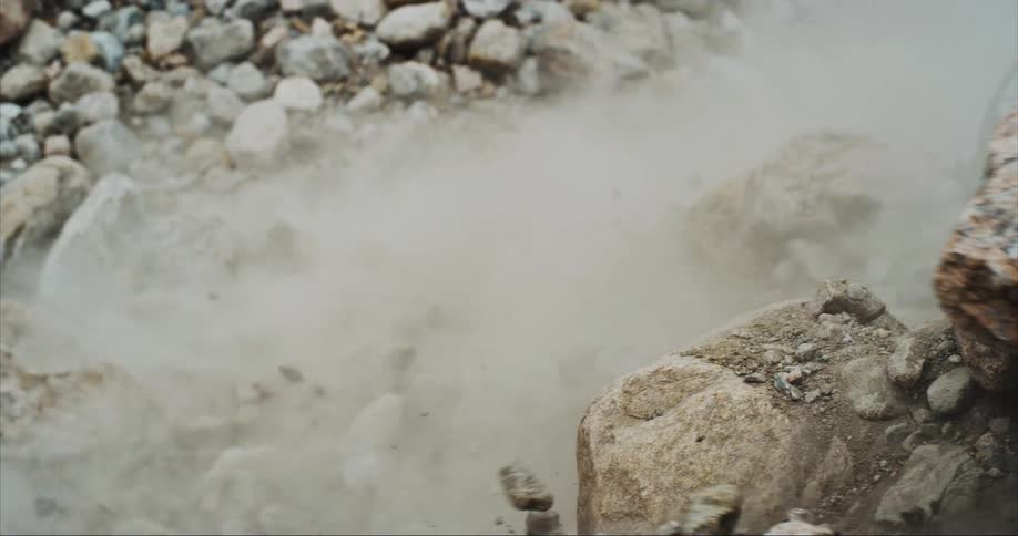 Slow motion of massive boulders cascading down a river valley