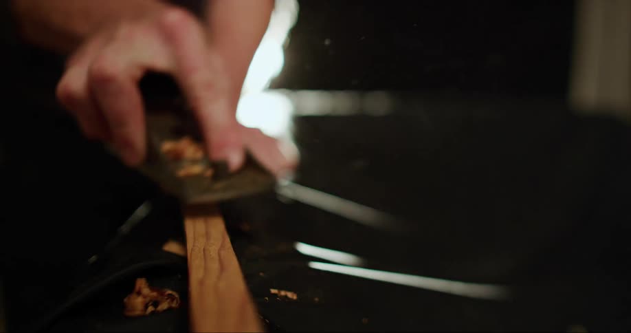 Male woodworker planes the surface of pieces of wood using a hand tool