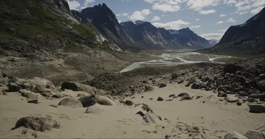 A view of a U shaped glacier carved river valley with high glacier covered peaks surrounding