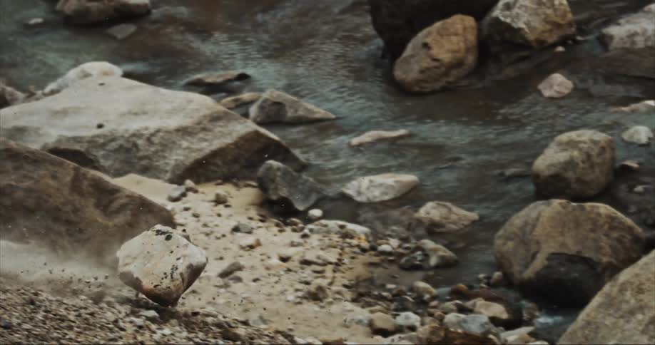 A massive boulder cascading down a mountainside and shattering at the bottom