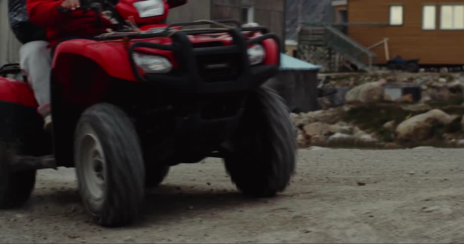 A man rides an atv down the dirt road near the Arctic circle