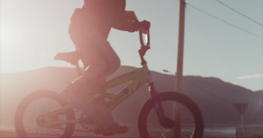 Backlit shot of boy riding  bmx bike with pure joy