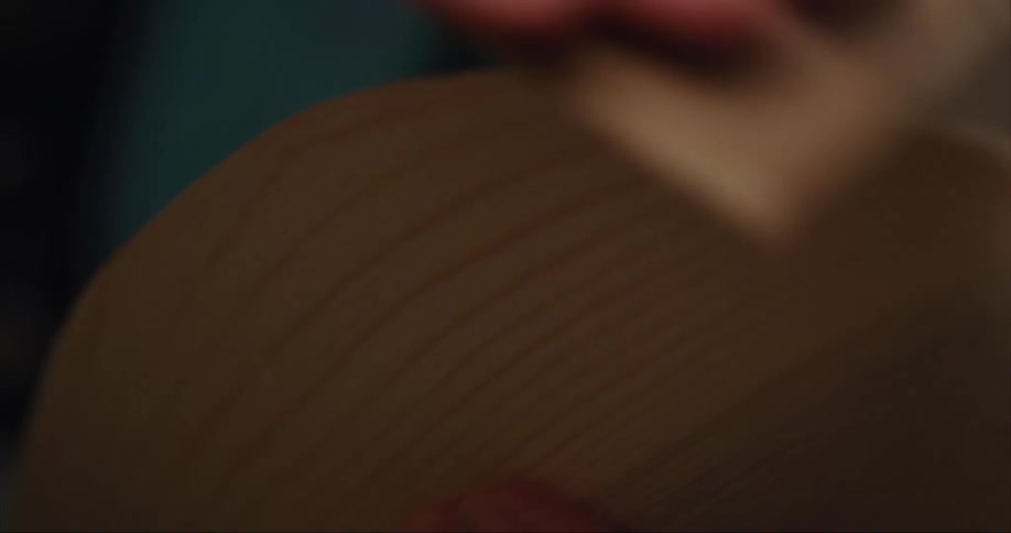 A man uses sand paper to sand wood while building his sea kayak from scratch