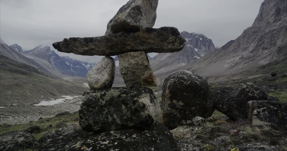 An Inukshuk, a stack of rocks balanced to mark the trail in snowy mountains in the wilderness of Baffin Island