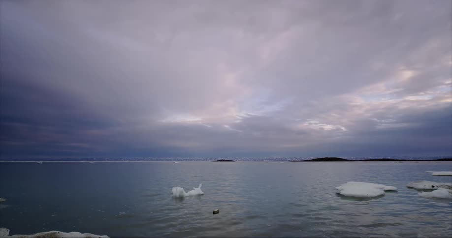 Blue skies with clouds over the arctic ocean with some floating sea ice