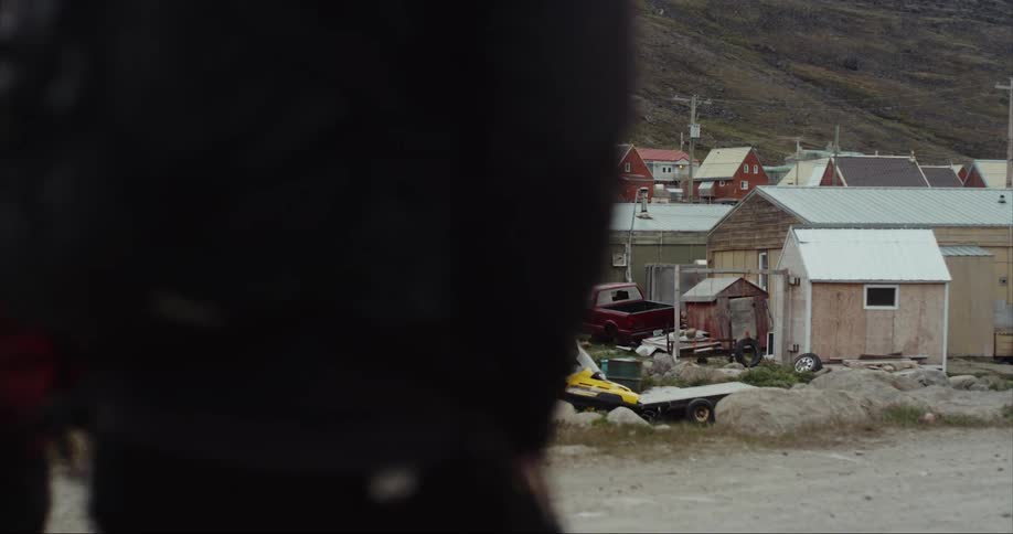 Two people walking near homes and sheds on a chilly day near the arctic circle