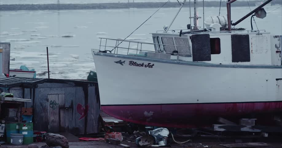 A white and red boat dry docked in an icy harbor