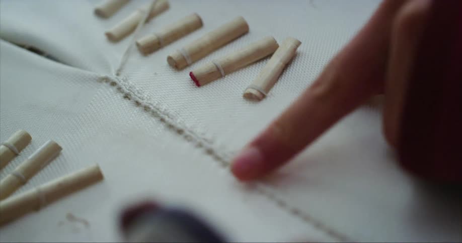 Two people examine seam in fabric while one holds thread