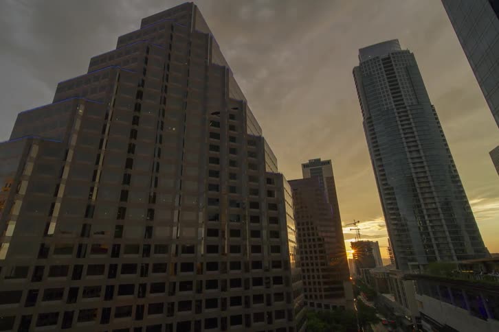 The sun shines and reflects off of glass buildings in a major city