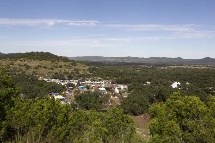 A busy town below is surrounded by hills and trees