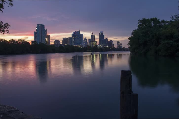 The sun rises behind a riverside city