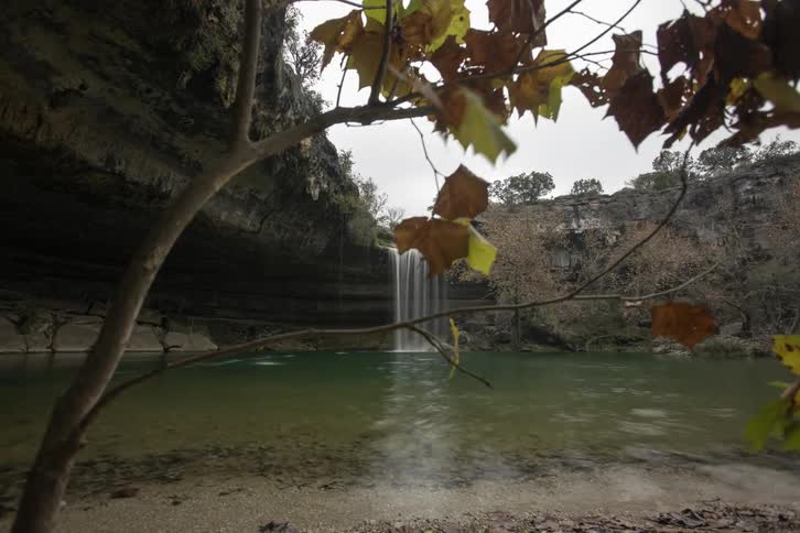 A waterfall spilling into a lake on a fall day