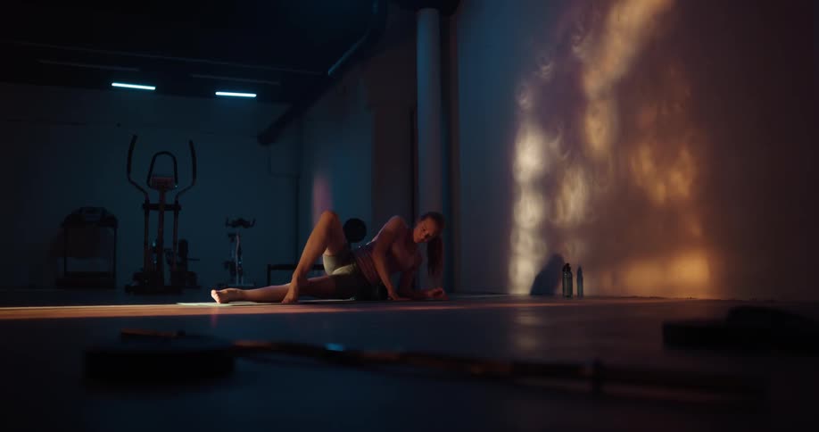 A woman stretching on a yoga mat in a fitness room