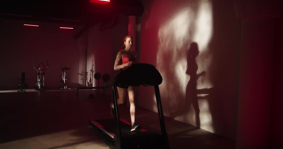 A woman is jogging on a treadmill in a gym