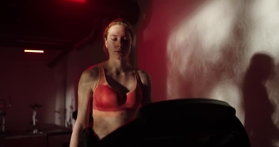 A woman looks nervous as she is walking on a treadmill in a gym