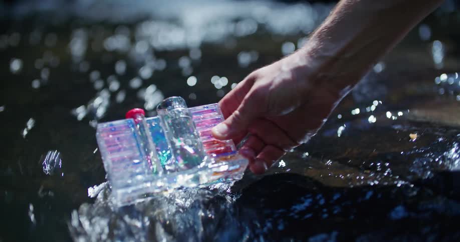Close up of hand filling test tube with water from stream