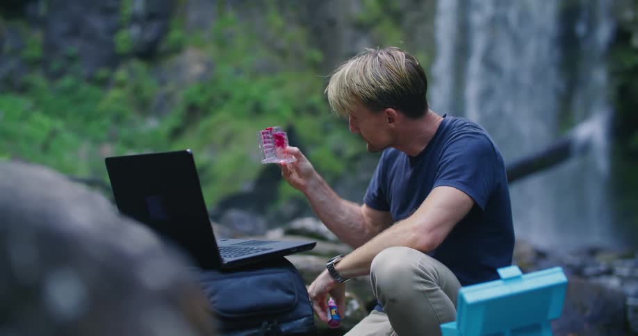 A man uses a dropper to test water at a waterfall
