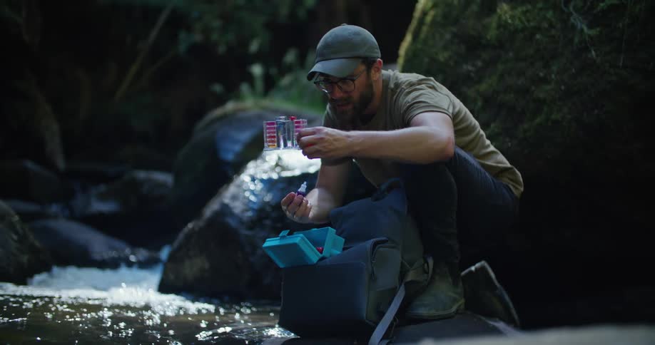 A scientist taking water samples from a stream in nature