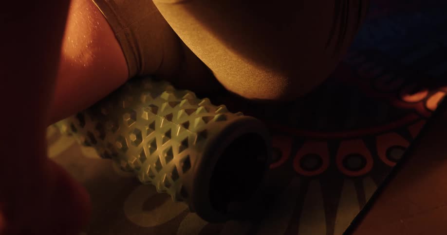 A woman uses a roller under her leg while stretching