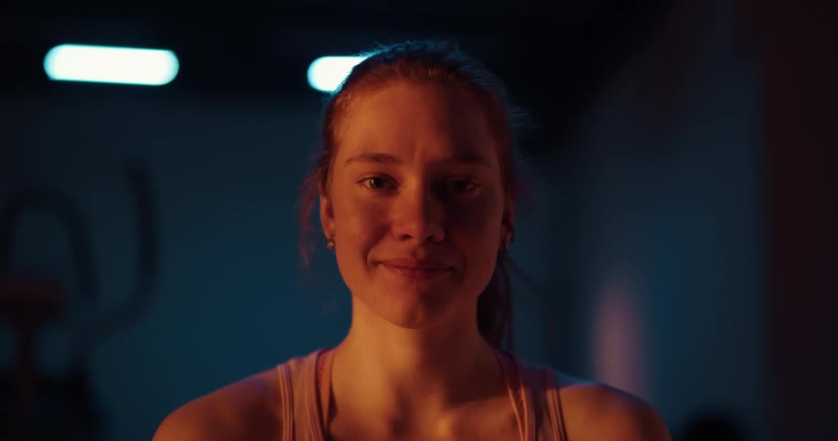 A woman poses and smiles as she stands in an exercise room